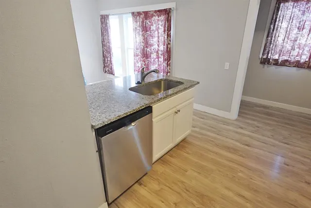 a kitchen with stainless steel appliances granite countertop a sink and a granite counter tops with wooden floors