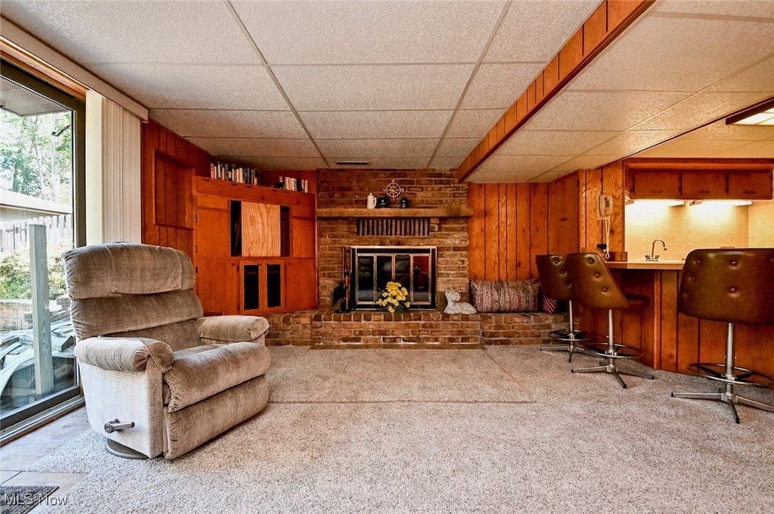 5653 Dailey Road New Franklin, OH 44319 - Photo 7 of 24 Living room featuring light carpet, a brick fireplace, sink, a drop ceiling, and wooden walls