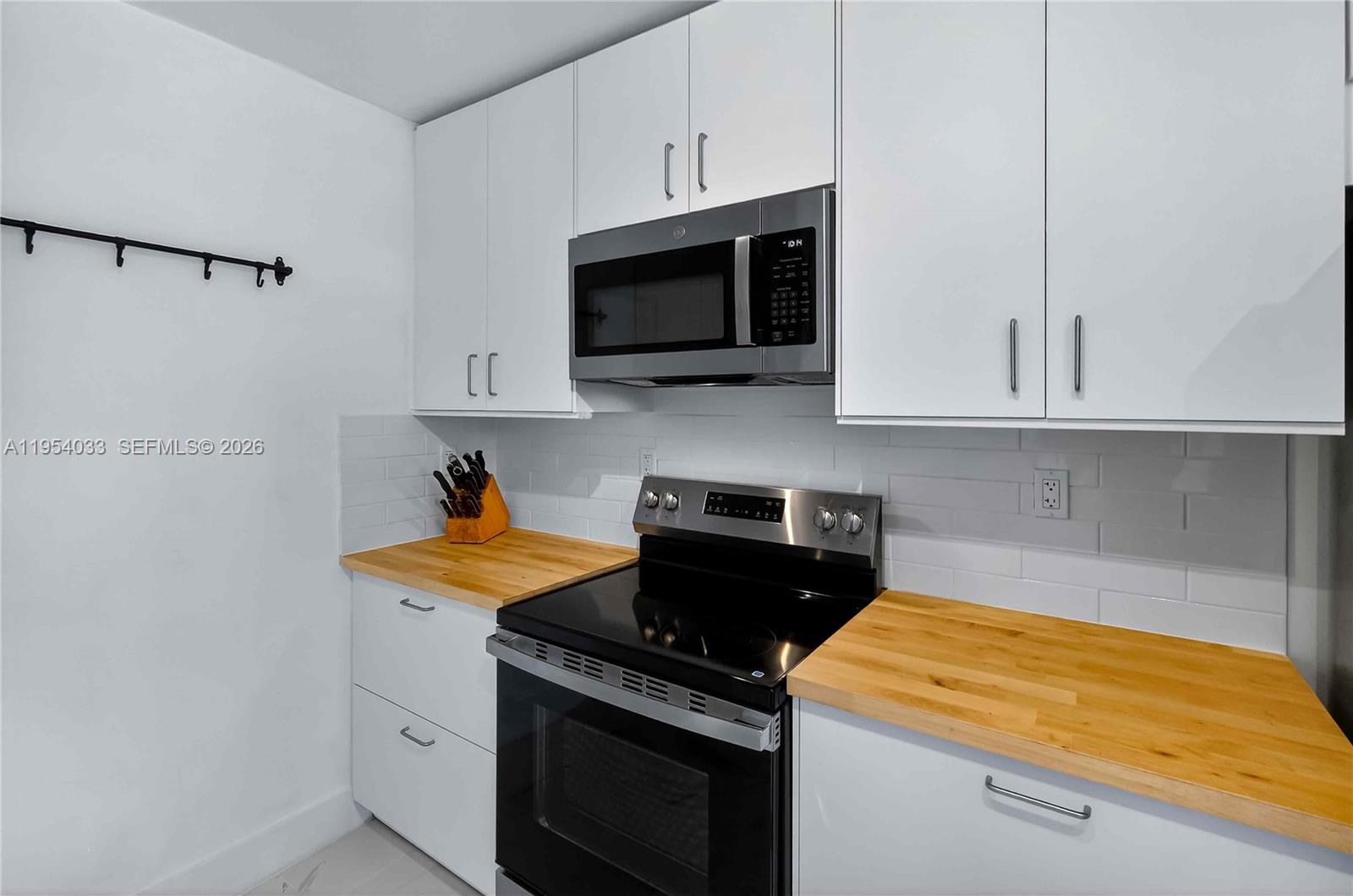 2399 Southwest 26th Lane Miami, FL 33133 - Photo 15 of 39 a kitchen with stainless steel appliances granite countertop white cabinets and a stove