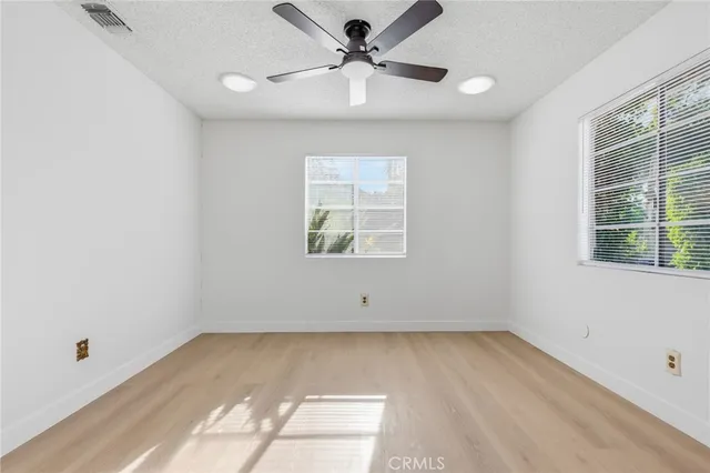 an empty room with ceiling fan and window