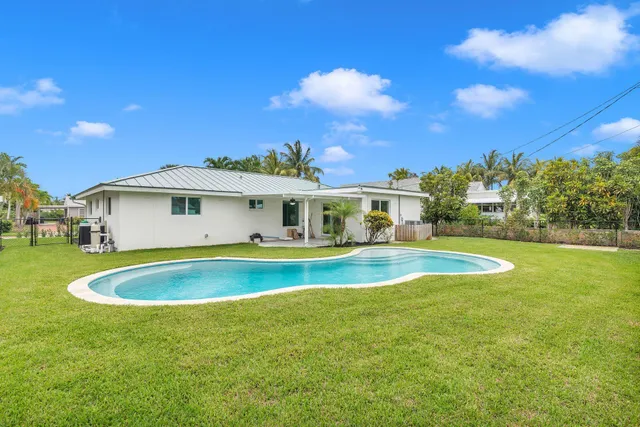 a view of pool with lawn chairs and large trees