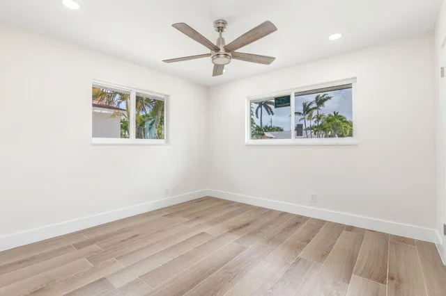 an empty room with wooden floor and ceiling fan