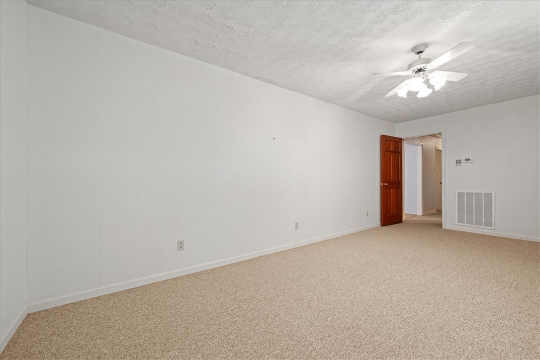 304 Shaw Road Honea Path, SC 29654 - Photo 15 of 39 This spacious room features neutral carpet and a ceiling fan, offering a comfortable and versatile living space.