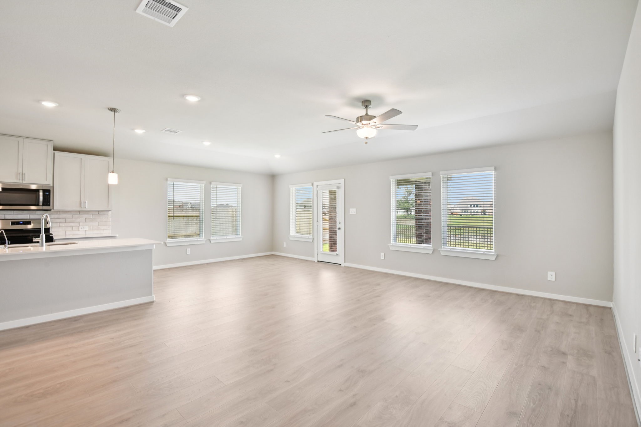 1672 Hopson Ranch Drive Conroe, TX 77301 - Photo 6 of 44 a view of an empty room with a kitchen stove and wooden floor