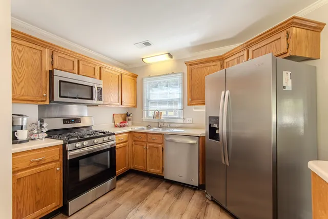 a kitchen with stainless steel appliances granite countertop a refrigerator a stove top oven a sink and dishwasher with wooden floor