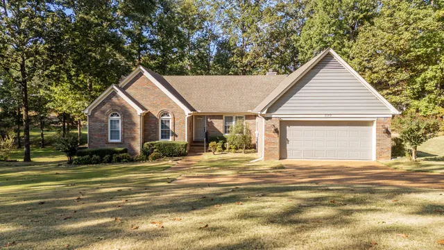a view of a house with a yard and large tree