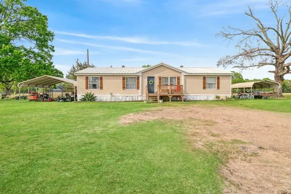 a view of a house with a big yard and large trees