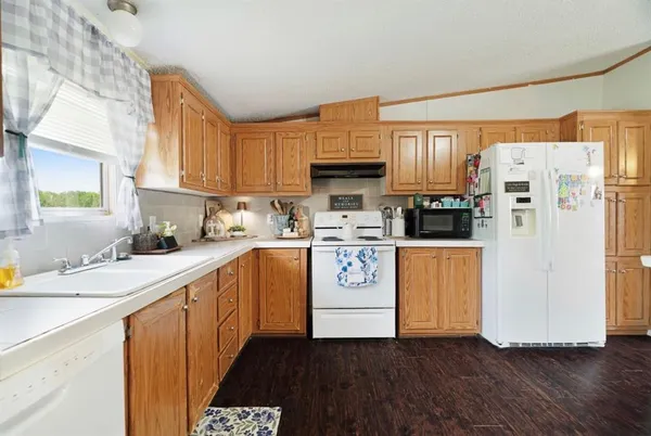 a kitchen with a refrigerator a stove a sink and white cabinets with wooden floor