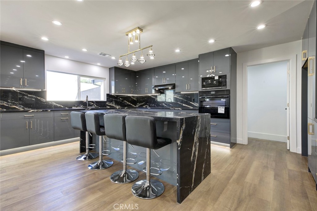 9055 Forbes Avenue Northridge, CA 91343 - Photo 11 of 62 a kitchen with stainless steel appliances kitchen island granite countertop a table chairs sink and cabinets