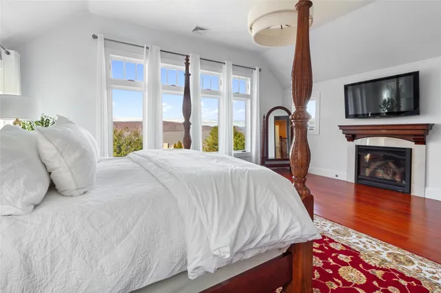 a bed sitting in a bedroom next to a window with a flat tv screen and a fireplace