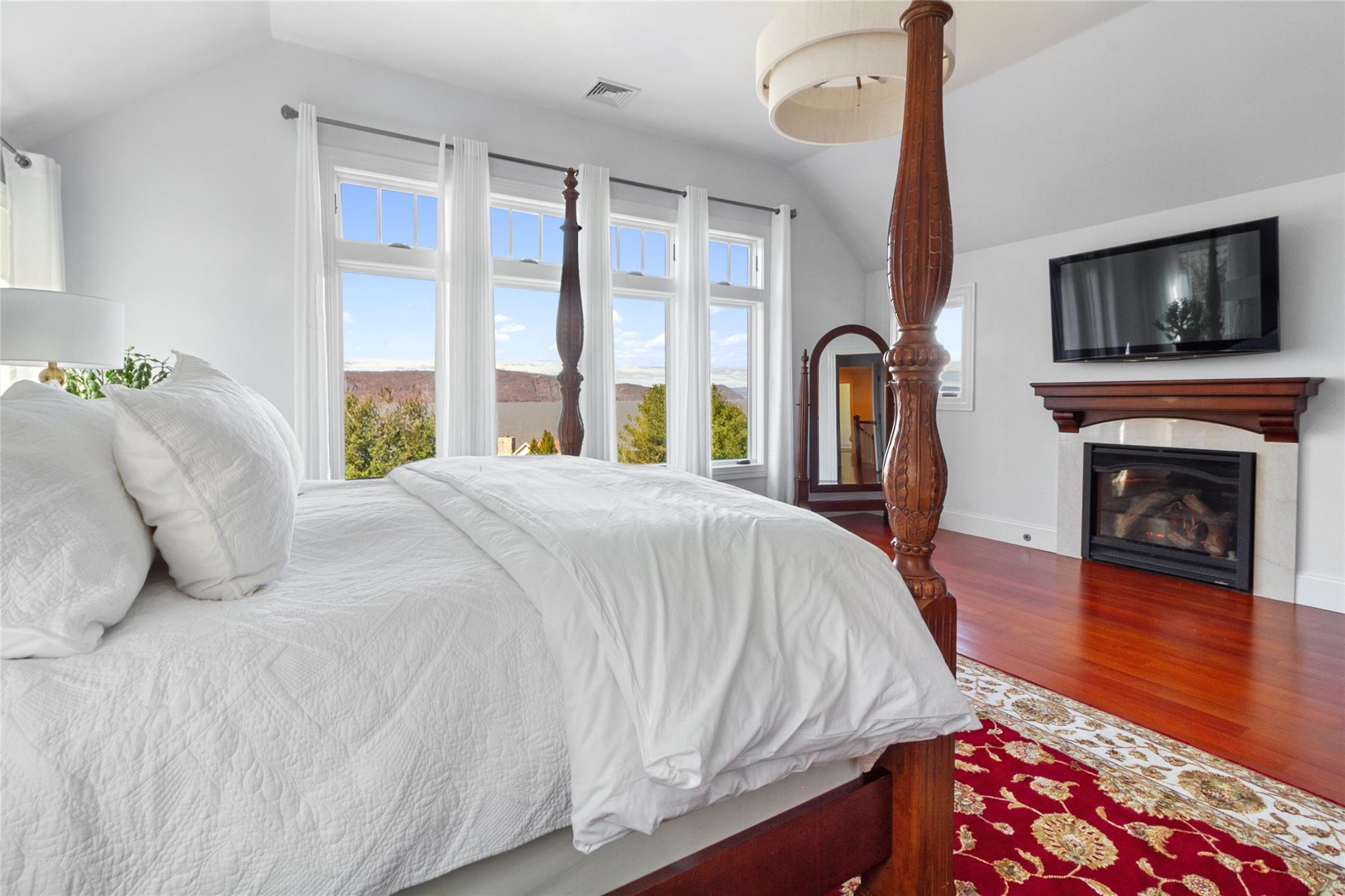 24 Country Club Lane Briarcliff Manor, NY 10510 - Photo 16 of 42 a bed sitting in a bedroom next to a window with a flat tv screen and a fireplace
