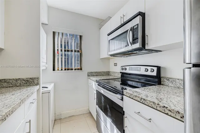 a utility room with granite countertop cabinets washer and dryer