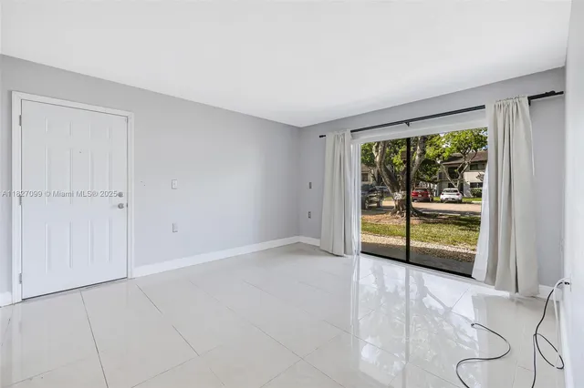 a view of an empty room with wooden floor and windows