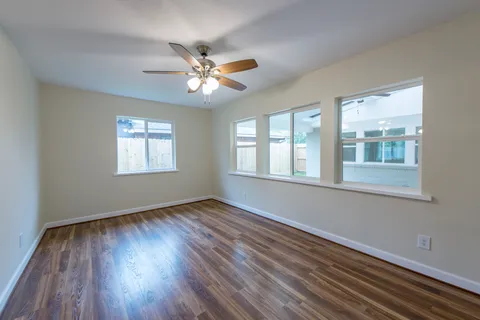 a view of an empty room with wooden floor and a window