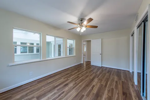 a view of an empty room with a window and wooden floor