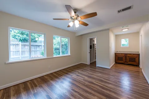 a view of an empty room with a window and wooden floor