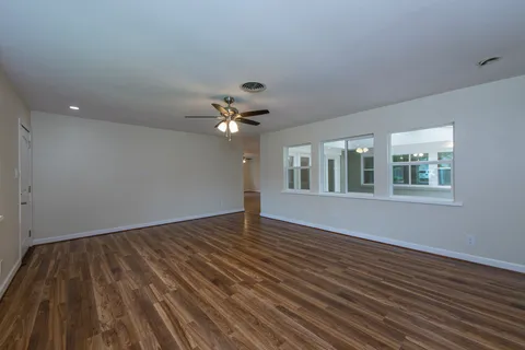 a view of an empty room with wooden floor and a window