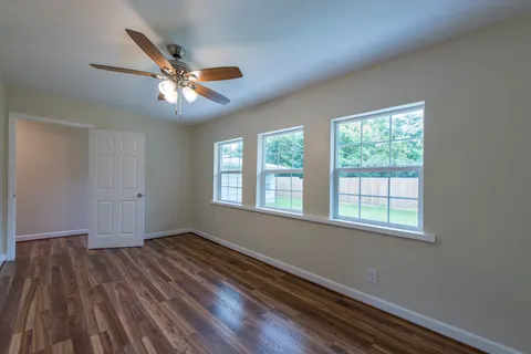 a view of empty room with wooden floor and fan