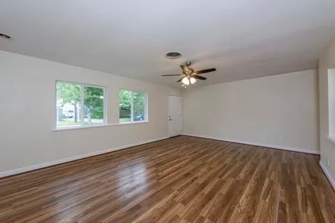 a view of empty room with wooden floor and fan