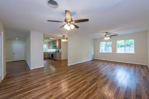 a view of an empty room with window and wooden floor