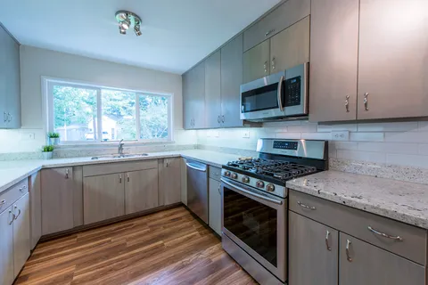 a kitchen with stainless steel appliances granite countertop a sink a stove a microwave and wooden cabinets