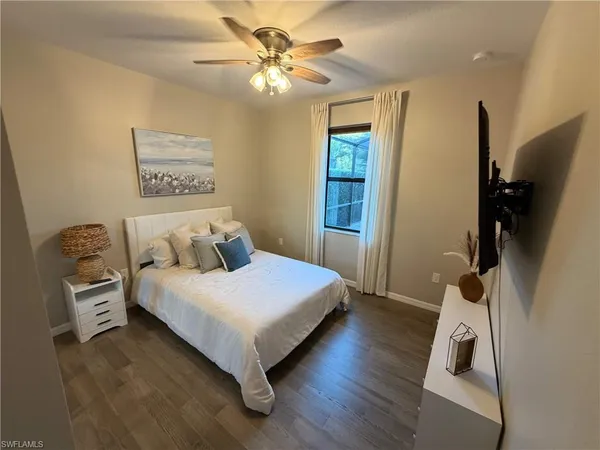 a bedroom with a bed and a flat tv screen on the dresser