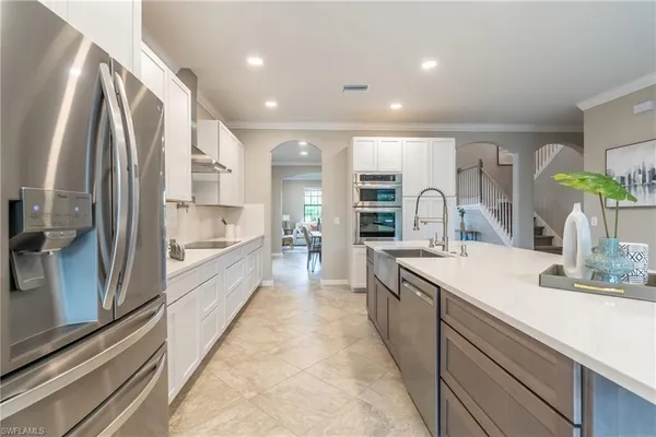 a large kitchen with a large counter top a sink stainless steel appliances and cabinets