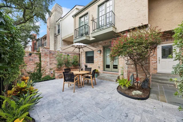 a view of a patio with table and chairs potted plants and large tree