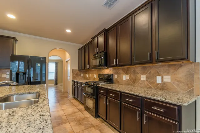 a kitchen with stainless steel appliances granite countertop a sink stove and cabinets
