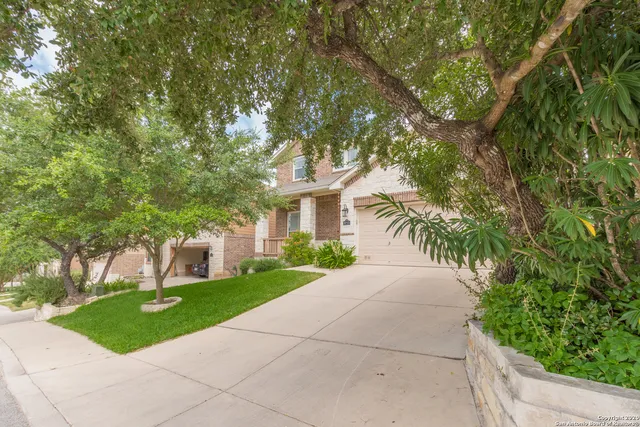 a front view of a house with a garden and trees