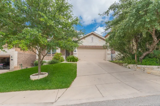 a front view of a house with a yard and a tree