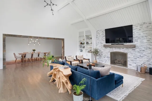 a open kitchen with stainless steel appliances granite countertop a stove a sink a oven a dining table and chairs with wooden floor