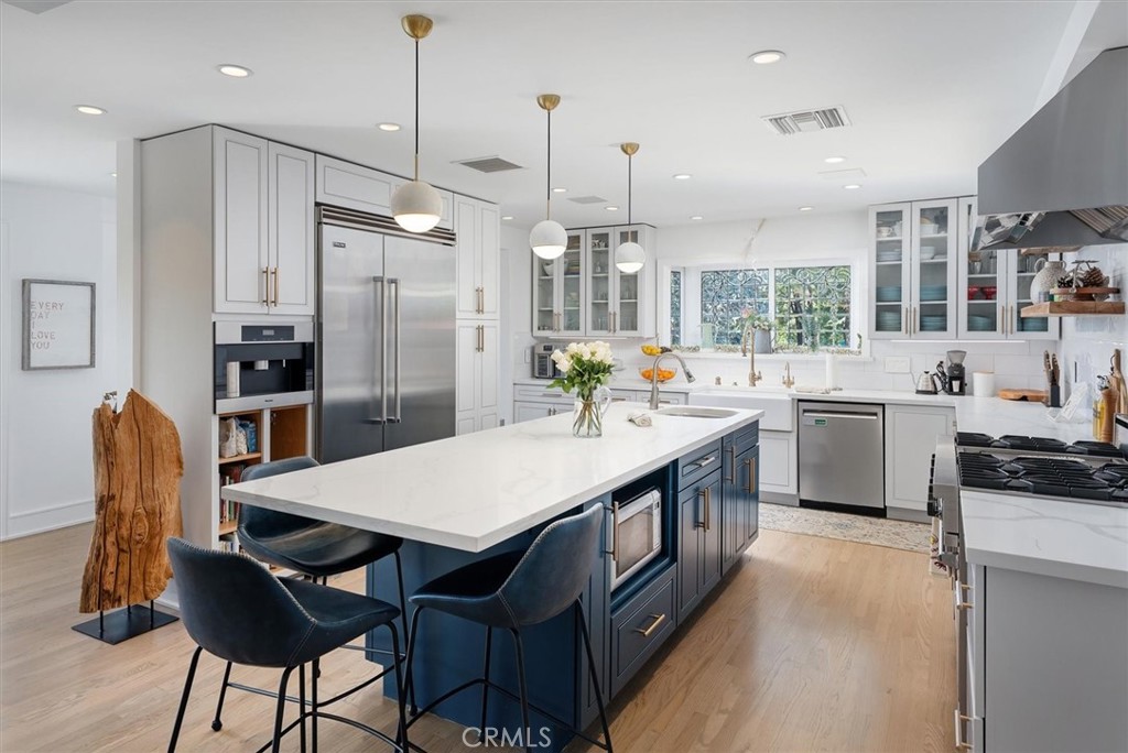 28933 Wagon Road Agoura Hills, CA 91301 - Photo 23 of 73 a open kitchen with stainless steel appliances granite countertop a stove a sink a oven a dining table and chairs with wooden floor