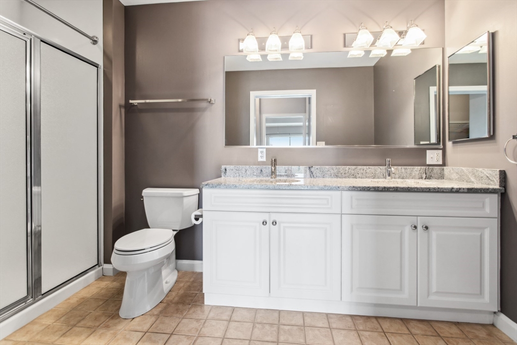 36 Village Road, Unit 404 Middleton, MA 01949 - Photo 27 of 41 a bathroom with a granite countertop sink toilet and a mirror