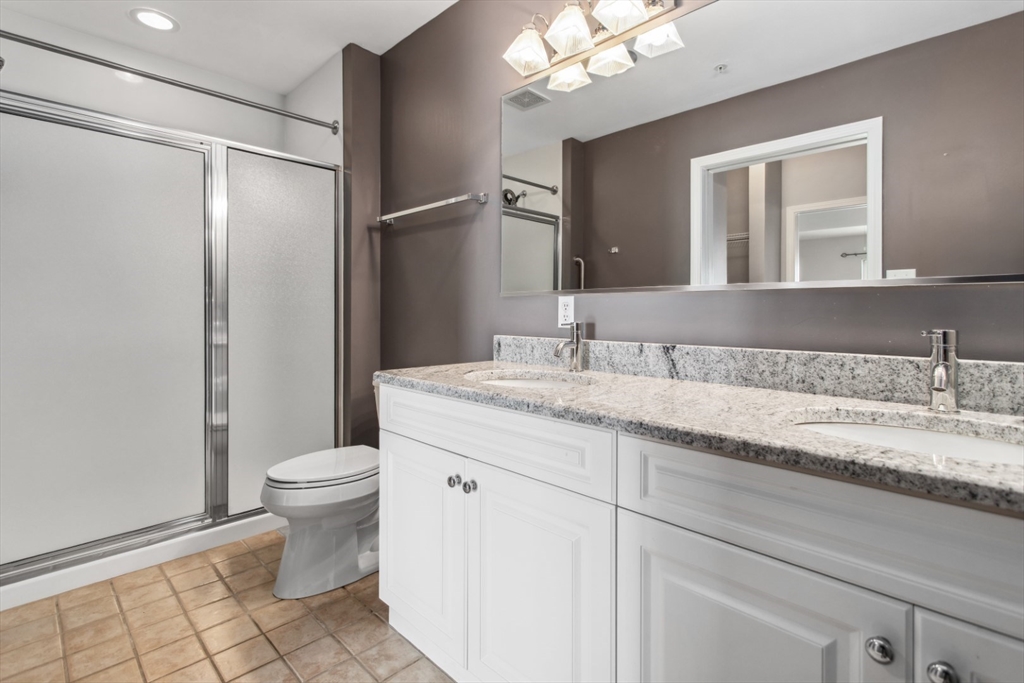 36 Village Road, Unit 404 Middleton, MA 01949 - Photo 28 of 41 a bathroom with a granite countertop sink a toilet and a mirror