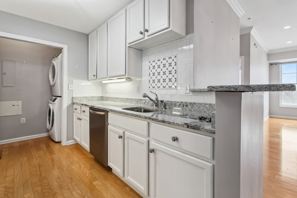 36 Village Road, Unit 404 Middleton, MA 01949 - Photo 9 of 41 a kitchen with stainless steel appliances granite countertop a sink and cabinets with wooden floor