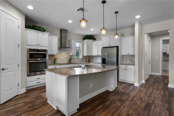 a kitchen with stainless steel appliances granite countertop a sink a stove and a refrigerator