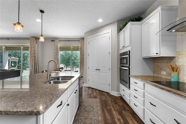 a kitchen with granite countertop a sink a counter space appliances and cabinets