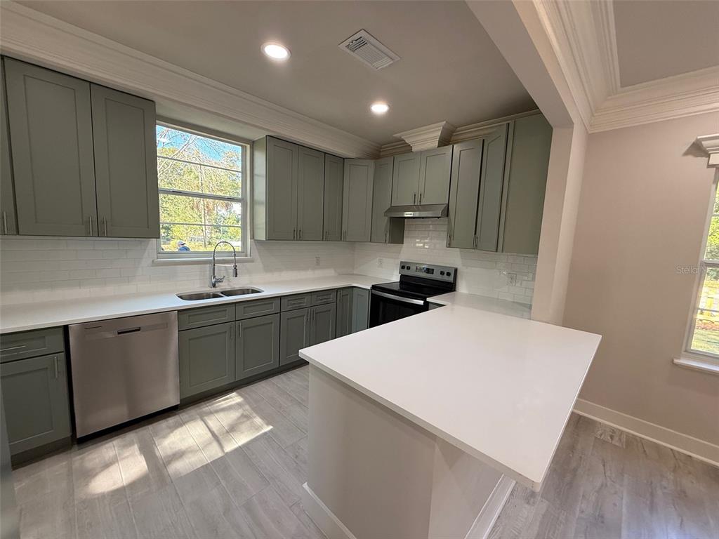 1217 Northeast 4 Street Gainesville, FL 32601 - Photo 11 of 36 a kitchen with kitchen island a sink a stove a refrigerator cabinets and a window