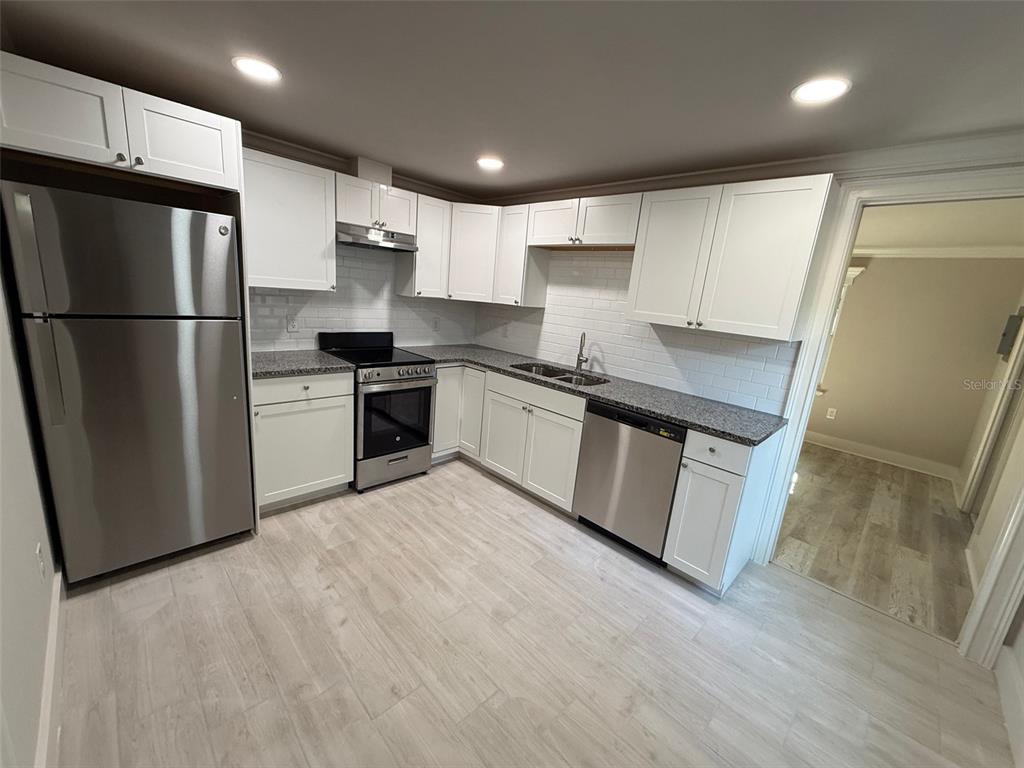 1217 Northeast 4 Street Gainesville, FL 32601 - Photo 29 of 36 a kitchen with stainless steel appliances granite countertop a refrigerator a stove a sink dishwasher and a refrigerator