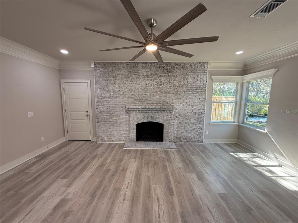 1217 Northeast 4 Street Gainesville, FL 32601 - Photo 7 of 36 an empty room with wooden floor a fireplace and windows