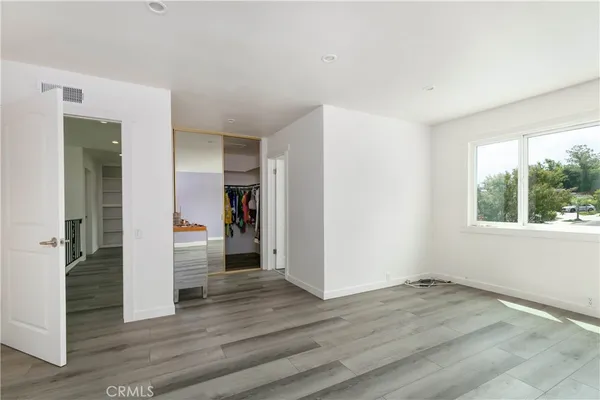 an empty room with wooden floor & windows