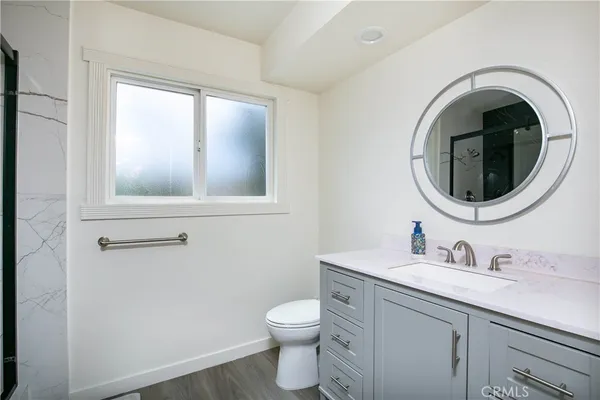 a bathroom with a granite countertop toilet a sink and mirror