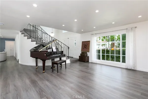 a view of a livingroom with furniture stairs wooden floor and windows