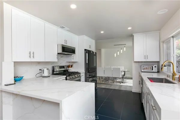 a kitchen with stainless steel appliances granite countertop a sink a stove and a refrigerator