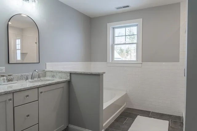 a bathroom with a granite countertop sink mirror and bathtub