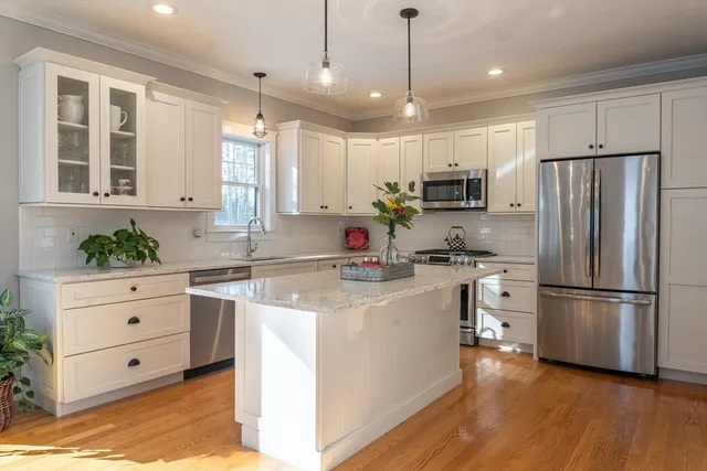 a kitchen with kitchen island white cabinets and stainless steel appliances