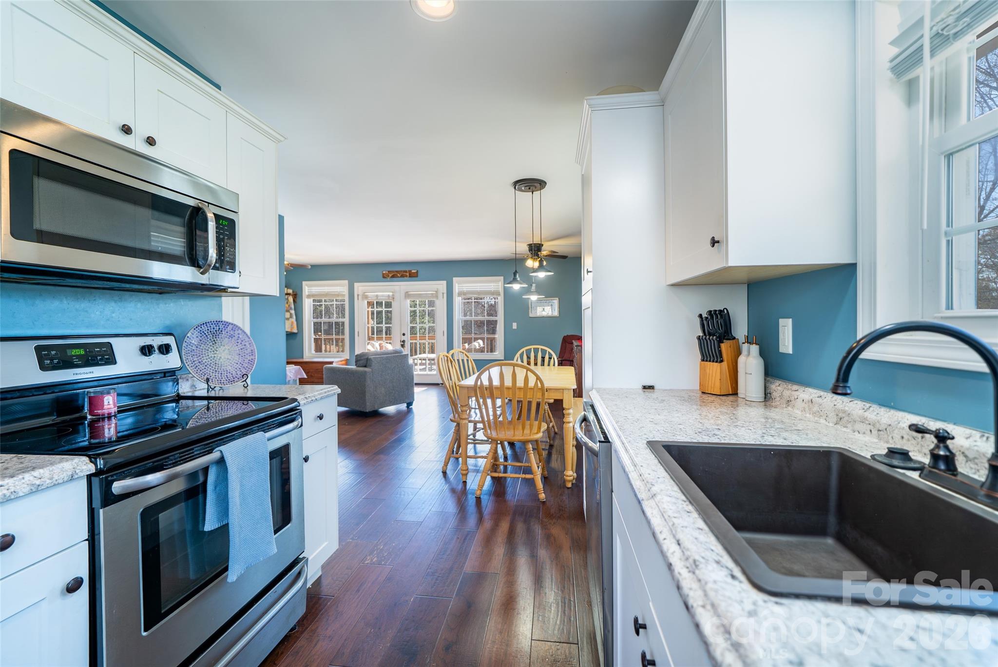 412 Masters View Drive Etowah, NC 28729 - Photo 10 of 30 a kitchen with stainless steel appliances granite countertop a stove top oven a sink dishwasher and white cabinets with wooden floor