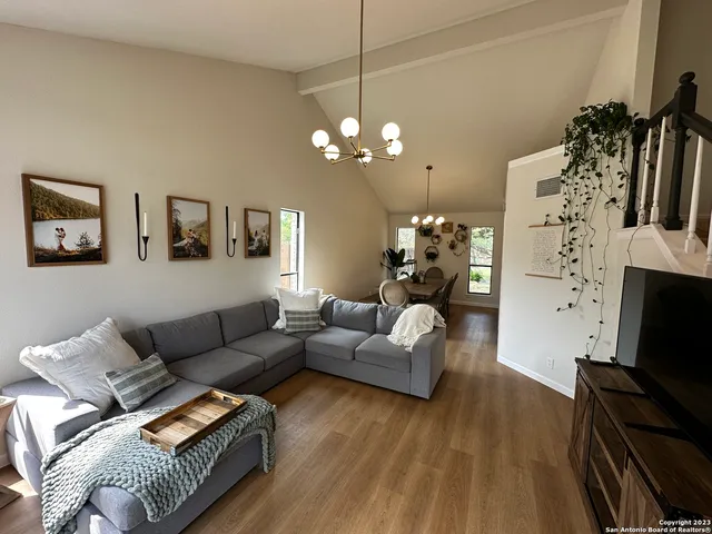 a living room with furniture a flat screen tv and a chandelier