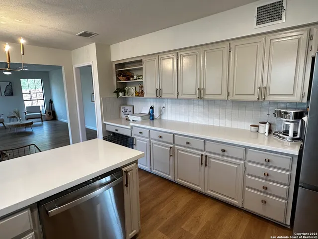 a kitchen with stainless steel appliances a stove a sink a refrigerator white cabinets and wooden floor